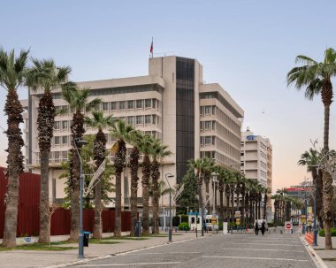 İzmir, Türkiye - 1 Nisan 2025: Palmiye ağaçları, binalar ve sokaklardaki insanlarla Kordon gezinti alanında kuyruk oluşturdu