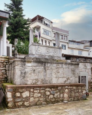 Arka planda dekoratif oymalar ve modern binalarla tarihi taş mezar, Uskudar, İstanbul, Türkiye 'deki Cinili Camii avlusunda