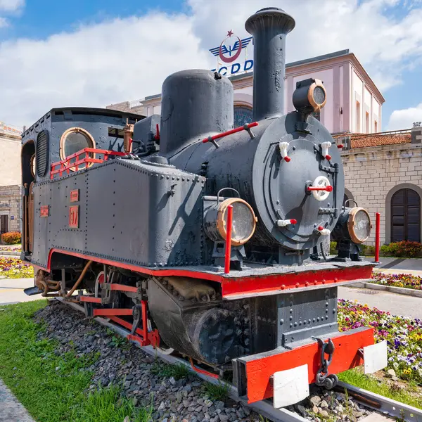 İzmir, Türkiye - 6 Nisan 2025: Tarihi TCDD buharlı lokomotif No. 97, Türk Devlet Demiryolları Binası, Konak Bölgesi. Çiçekler arasında sergilenen kırmızı süslemeli klasik siyah motor