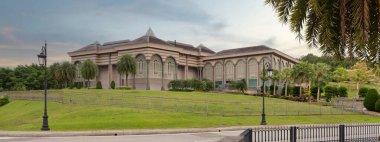 Brunei 'nin Bandar Seri Begawan kentindeki başbakanlık ofisinde canlı yeşilliklerle çevrili karmaşık bir mimari yer alıyor. Bu simge Bruneis 'in politik önemini ve doğal güzelliğini temsil ediyor.