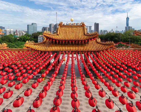 Kuala Lumpur, Malezya 'daki Thean Hou Tapınağı' nın çarpıcı mimarisi. Parlak kırmızı fenerlerle süslenmiş ve modern bir şehir silüetiyle çevrili.