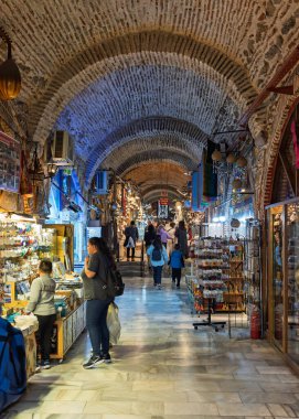 İzmir, Türkiye - 31 Mart 2025: Kizlaragasi Han Çarşısı 'nda gezen ziyaretçiler, geleneksel el sanatları ve hediyelik eşyalarla dolu çeşitli dükkanları geziyor