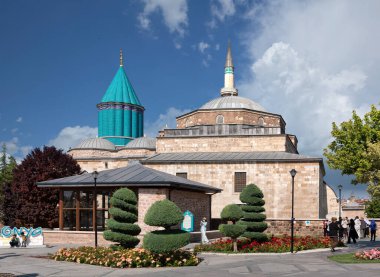 Konya, Turkey - June 7, 2025: The Mevlana Museum, mausoleum of Rumi. View of the iconic turquoise dome and minaret with gardens under a blue sky on a sunny day