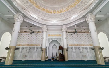Kuala Lumpur, Malezya 'daki El-Buhari Vakfı Camii' nin iç mimarisi, beyaz sütunlar, altın Arap kaligrafisi, karmaşık bir kubbe tavanı, bir mihrab, bir minbar ve yeşil bir dua halısına sahip.