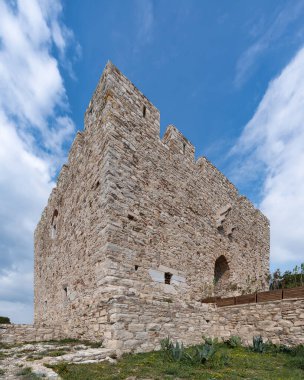 Tarihsel Guvercinada Kalesi, veya Kucckada, mavi gökyüzünün altında beyaz bulutlu taş kale duvarları, Kusadasi, Türkiye. Düşük açı görünümü
