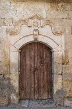 Eski ahşap kapılı, paslı donanımlı, süslü, taş kemerli bir kemerli yıldız motifli. Eski taş duvar dokusu. Tarihi mimari ayrıntı