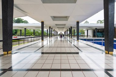 Ulusal Cami 'deki modern koridor, ya da Mescid Negara, Kuala Lumpur, Malezya. Siyah sütunlar, beyaz tavan, döşeme döşemesi ve yansıtıcı havuz.