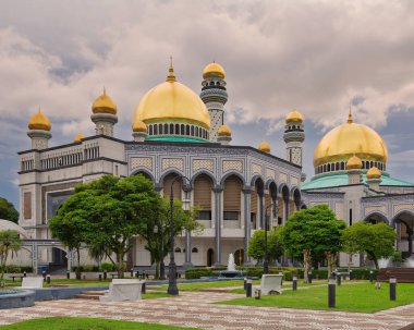 Jame Asr Hassanil Bolkiah Camii, Bandar Seri Begawan, Brunei. Altın kubbeler, minareler ve bulutlu bir gökyüzü altında gün batımından önce karmaşık mimari
