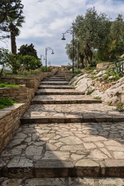 Guvercinada 'daki taş basamaklar ve duvarlar, veya Güvercin Adası, zeytin ağaçları ve sokak lambaları bulutlu bir gökyüzü altında, Kusadasi, Türkiye