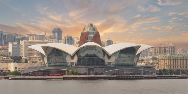 Alacakaranlıkta Azerbaycan 'ın Bakü kentindeki Hazar Denizi kıyısındaki modern Deniz Mall binası. Şehir silueti ve bulutlu gökyüzü ile ayırt edici mimari