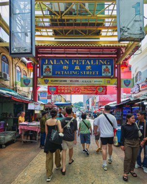 Kuala Lumpur, Malezya - 16 Şubat 2025: Bustling Petaling Sokağı, veya Çin Mahallesi. İnsanlar sembolik Jalan Petaling kemer yolunun altındaki market tezgahlarının önünden geçiyorlar. Canlı sokak sahnesi