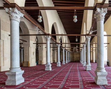 Al-Zahir Baybarları Camii, Kahire, Mısır. Süslü mermer kolonlar, kırmızı dua halısı ve ahşap tavanların altında asılı lambalar. Tarihi İslami mimari