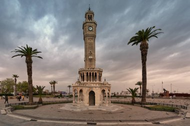 İzmir, Türkiye - 4 Nisan 2025: İzmir Saat Kulesi, Türkçe: Saat Kulesi, Konak Meydanı. Osmanlı mimarisini bulutlu gökyüzünün altında palmiye ağaçlarıyla süslemek