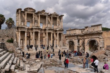 İzmir, Türkiye - 2 Nisan 2025: Celsus Kütüphanesi, Efes. Turistler bulutlu bir gökyüzünün altındaki antik Roma kalıntılarını keşfediyorlar.