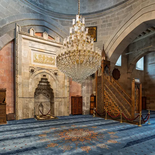 Kayseri Büyük Camii 'nin çarpıcı iç mimarisi, Türkçe: Ulu Camii, Kayseri, Türkiye. Süslü mihrab, karışık oyulmuş minbar, ve üzerinde büyük kristal avize desenli mavi halı