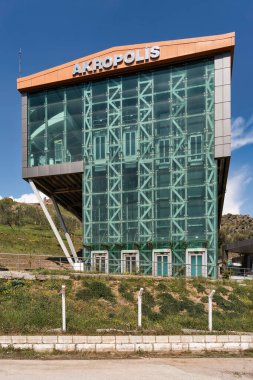 AKROPOLIS işareti taşıyan Pergamon Acropolis Kablo Otomobil İstasyonunun modern cam binası, Bergama, İzmir, Türkiye. Güneşli gün, mavi gökyüzü, yeşil yamaç