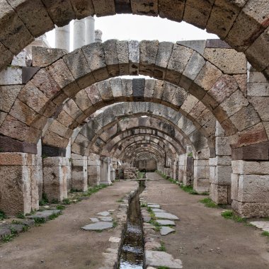 İzmir 'in İzmir ilinin antik Roma Agora kentinin kemerli koridoru. Taş kemerler ve merkezi bir su kanalı bu tarihi arkeolojik alanı tanımlar