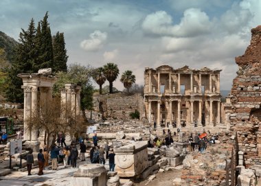 İzmir, Türkiye - 2 Nisan 2025: Celsus Kütüphanesi, antik Roma kenti Efes, Selcuk. Turistler bulutlu bir gökyüzünün altındaki kalıntıları keşfediyorlar.