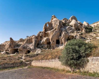 Ancient cave dwellings in the unique fairy chimneys of Goreme, Cappadocia, Turkey, under a clear blue sky
