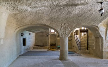 Interior of Cavusin Koyu Eski Kaya Camii, or Cavusin Old Rock Mosque, ancient rock-cut mosque in Cavusin, Cappadocia, Turkey. Features carved stone architecture, arches, and floral column