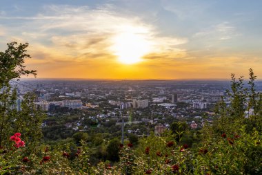 20 Temmuz 'da Kok Tobe Parkı' ndaki şehir manzarasında teleferik kulübesi ve gül bahçesi.