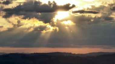 Kırsal hayat manzarasında huzurlu bir gün batımı. Kırsal kesimde gün batımı. Gün batımında bulutlar arasında güneş ışınları. Günbatımı gökyüzü manzarası. Renkli ufuk çizgisi. Renkli ufuk çizgisi. Bulutlar arasında güneş ışınları.