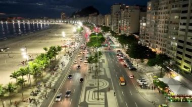 Night Traffic At Copacabana Beach In Rio De Janeiro Brazil. Dark Night Life Skyline. Tourism Scenery. Copacabana Beach At Rio De Janeiro Brazil. Dark Evening Skyline. Dark Skyline.