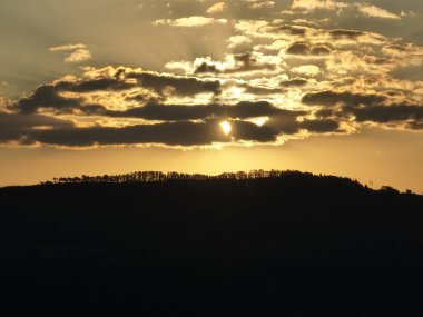 Kırsal kesimde çiftçilik yaparken gün batımı. Dağlar arasında yeşil orman ağaçları.