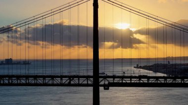 Lizbon 'daki Lizbon Bölgesi' nde 25 Nisan Köprüsünde Günbatımı Gökyüzü. Şehir merkezinde gün batımı. Freeway Yolu Manzarası. Portekiz Lizbon 'da 25 Nisan Köprüsü. Toplu Taşıma Manzarası.