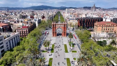 Barselona İspanya 'da Arc De Triomf. İnsansız hava aracı, etrafı gür ağaçlarla çevrili kaldırımlı bir bahçe yakalıyor. Şehir merkezindeki iş dünyası. Şehir merkezinin dışında Panning Wide 'da. Barselona İspanya.