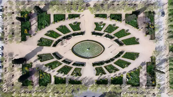 Katalonya 'nın Barselona bölgesindeki Ciutadella Parkı. İnsansız hava aracı, etrafı gür ağaçlarla çevrili kaldırımlı bir bahçe yakalıyor. İş Bulutları Gökyüzü Şehir Merkezi. Arkaplan Panoramik Şehir.