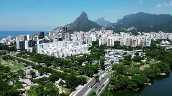 Rio de Janeiro Brezilya 'daki Rodrigo De Freitas Gölü. Etrafı yemyeşil tropikal yağmur ormanlarıyla çevrili bir nehrin havadan görünüşü. Şehir merkezindeki iş bulutları gökyüzünü bulutlandırıyor.