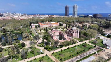 Barselona 'daki Katalonya Parlamentosu. İnsansız hava aracı, etrafı gür ağaçlarla çevrili kaldırımlı bir bahçe yakalıyor. İş Bulutları Gökyüzü Şehir Merkezi. İş dünyası geniş çaplı. Barselona İspanya.