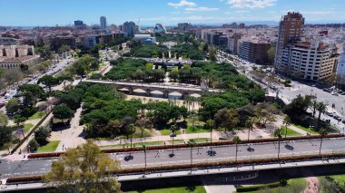 Valencia İspanya 'daki Turia Bahçeleri. İnsansız hava aracı, etrafı gür ağaçlarla çevrili kaldırımlı bir bahçe yakalıyor. Metropolitan Manzara Gökdelenleri. Güzel. Metropolitan Şehir. Valencia İspanya.