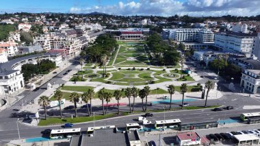 Portekiz 'in Cascais Lizbon bölgesindeki Estoril Kumarhanesi. İnsansız hava aracı, etrafı gür ağaçlarla çevrili kaldırımlı bir bahçe yakalıyor. İnşaat Manzarası Panoramik Şehir Görünümü Meşgul. Panoramik Şehir Görünümü.