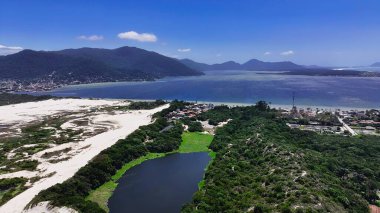 Florianopolis Santa Catarina Brezilya 'daki Conceicao Gölü. Etrafı yemyeşil tropikal yağmur ormanlarıyla çevrili bir nehrin havadan görünüşü. Shore Sky Clouds Plaj Denizi. Uluslararası Plaj Panoraması.