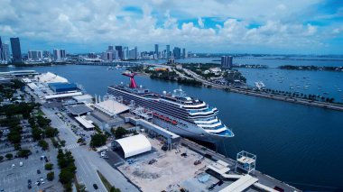 Miami, Florida, ABD 'deki Miami Limanı' nda bir yolcu gemisi. Sakin bir mavi okyanusa demirlemiş büyük bir beyaz gemi. Metropolitan Manzara Gökdelenleri. Güzel. Metropolitan Şehir. Miami Florida.
