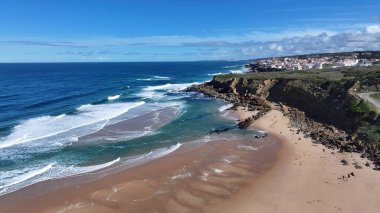 Lizbon 'un Sintra bölgesindeki Praia Grande Plajı. Turkuaz Okyanus Dalgaları Tropik Sahile Yavaşça Çarpıyor. Sahil Bulutları Yaz mevsimi. Sahil Kapısı Kapsama Alanı Geniş.