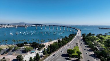 San Diego, Kaliforniya 'daki Conorado Bay Köprüsü. Karşıdan karşıya geçen arabalarla süspansiyon köprüsünün kuşbakışı görüntüsü. İş Bulutları Gökyüzü Şehir Merkezi. Geniş İş Döndürme.