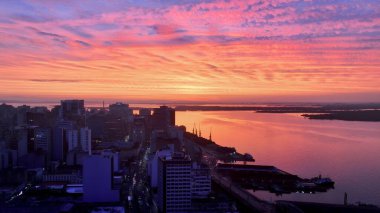 Porto Alegre Rio Grande Do Sul Brezilya 'da Sunset Skyline. Etrafı yemyeşil tropikal yağmur ormanlarıyla çevrili bir nehrin havadan görünüşü. Metropolitan Şirketi Binası Canlı Bina.