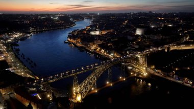 Porto Portekiz 'de Günbatımı I. Luis Köprüsü. Trafik, modern bir kablolu yayın konsolu köprüsünün karşısına geçiyor. İnşaat endüstrisi Skyline binaları meşgul. Endüstriyel Şehir Binaları. Porto Portekiz.