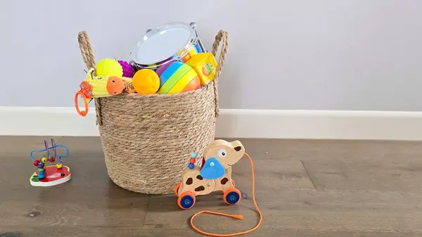 Tahta zeminde ahşap bir köpeğin olduğu sepetteki çocuk oyuncakları.. 