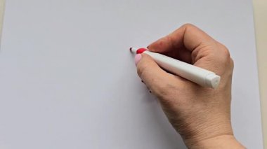 Beyaz kağıda işaretli kırmızı bir kalp çizen bir el. Minimalist ve yaratıcı tasarım aşkı, duyguları ve kişisel ifadeyi sembolize eder. Sevgililer Günü, DIY projeleri ya da yaratıcı çizimler için mükemmel..