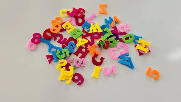 Beyaz bir masaya dağılmış renkli keçeli harfler. Eğitim faaliyetleri, DIY el sanatları ve çocuklar için yaratıcı öğrenme içeriği için mükemmel..