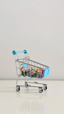 Noel temalı silgi ve renkli sahte taşlarla dolu mini alışveriş arabası Noel ruhunun neşeli ve şenlikli bir sembolü, küçük hediyeler ve neşeli mevsimsel detaylar..