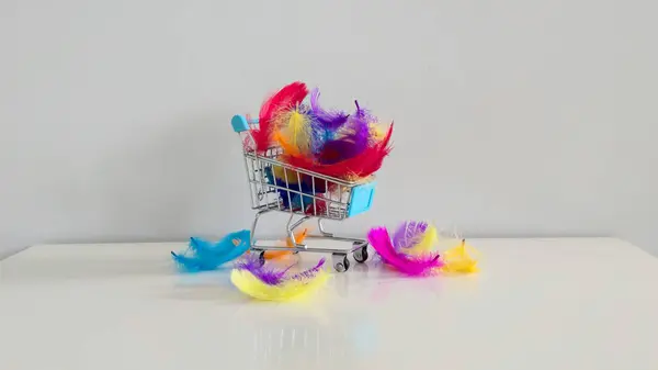 Rengarenk tüylerle dolu mini alışveriş arabası özgürlüğün, yaratıcılığın ve tüketicilerin yönlendirdiği dünyadaki seçimlerin yumuşaklığının hafif ve tuhaf bir sembolü..