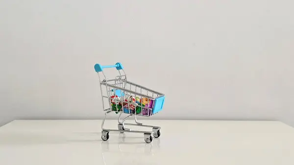 Noel temalı silgi ve renkli sahte taşlarla dolu mini alışveriş arabası Noel ruhunun neşeli ve şenlikli bir sembolü, küçük hediyeler ve neşeli mevsimsel detaylar..