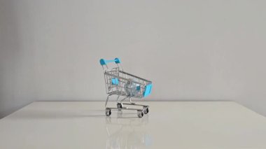 Bir el nazikçe küçük bir oyuncak alışveriş arabasını pastel Noel ağacıyla doldurur. Yumuşak, sembolik bir tatil hazırlığı ve şenlikli dekora para harcamak..