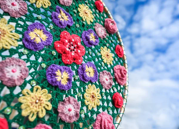 Tığ işi çiçek süslemesi açık havada mavi bir gökyüzüne karşı.