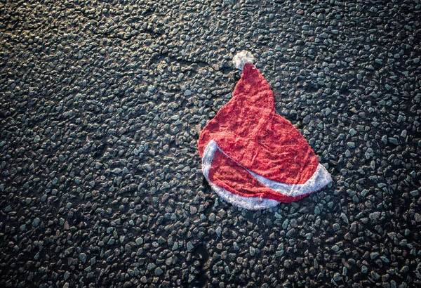 Stock image A squashed Santa hat with tyre marks in the middle of a road.